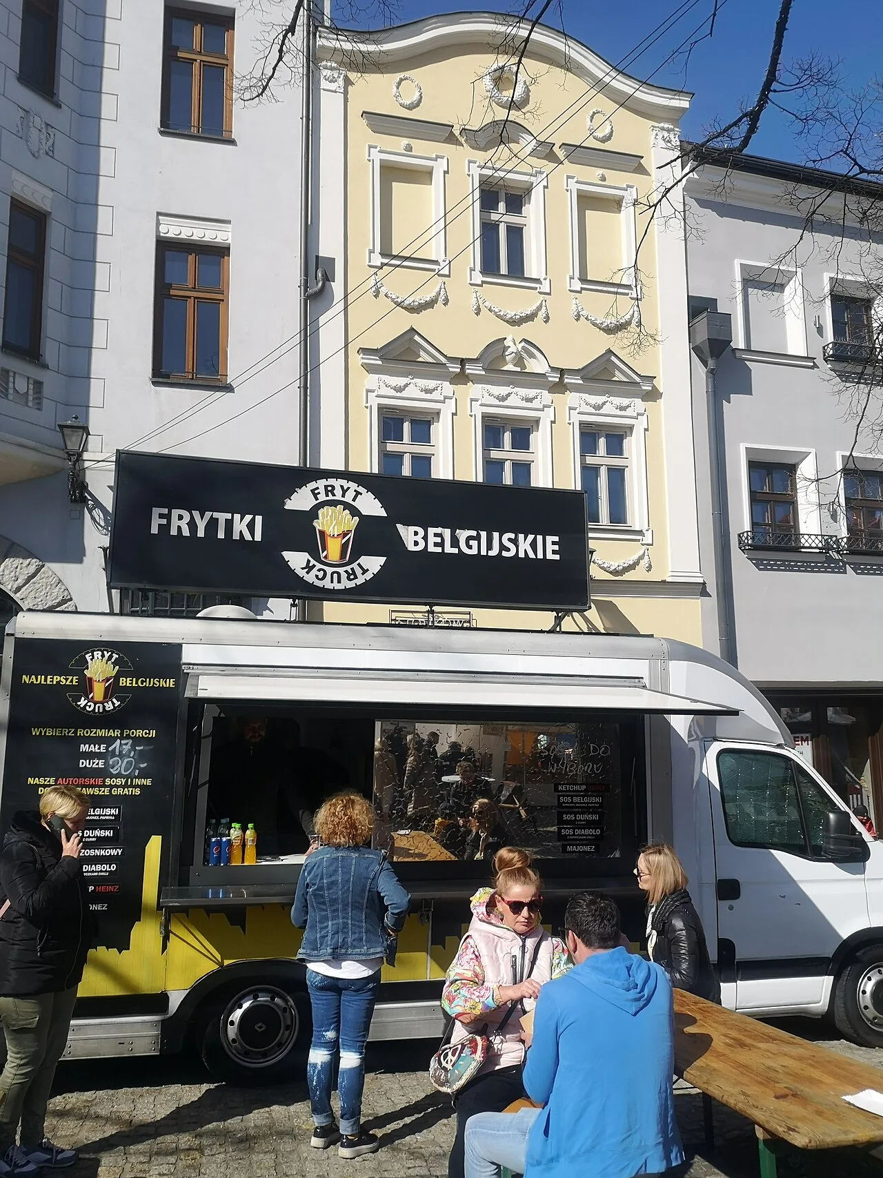 Belgische frietkraam met het opschrift Frytki Belgijskie (Belgische frieten) voor een historisch gebouw