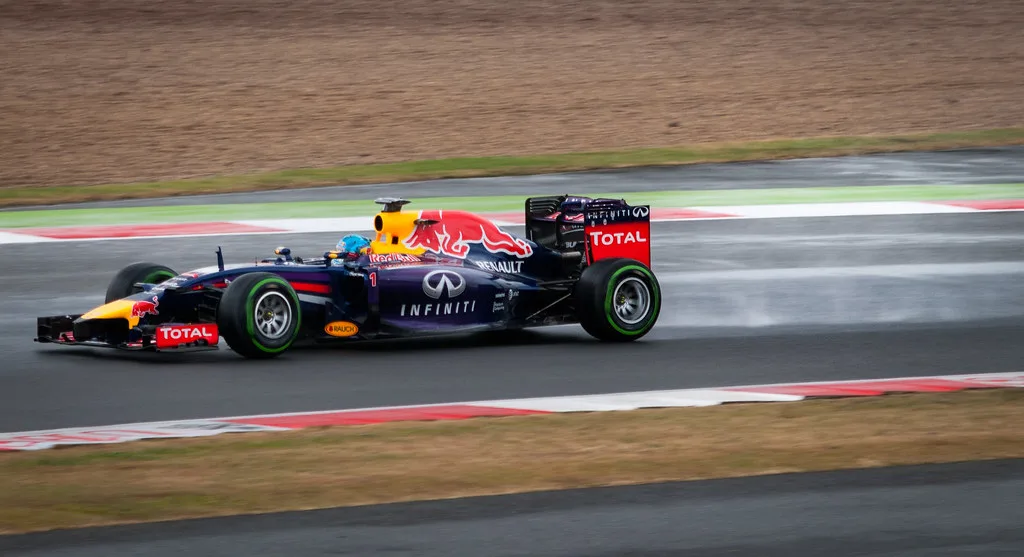 Formule 1-auto op groene intermediates op een nat circuit met spray achter de wielen