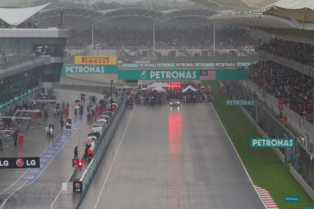 F1-startveld op een nat circuit met volgepakte tribunes op de achtergrond