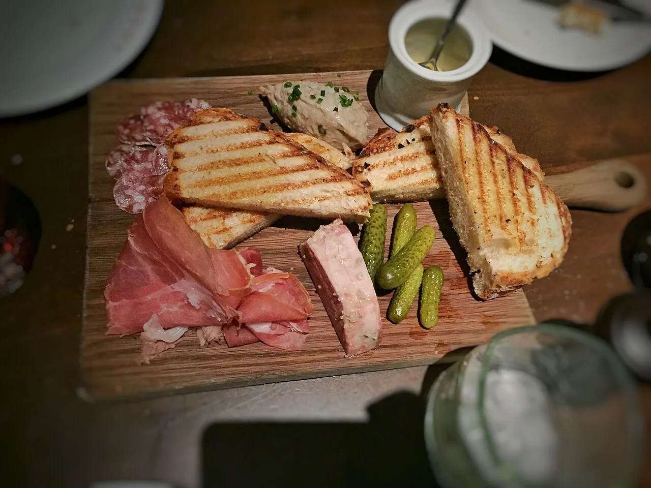 Houten plank met pâté, ham, saucisson, cornichons en geroosterd brood — klassieke charcuterie zoals in de Ardennen